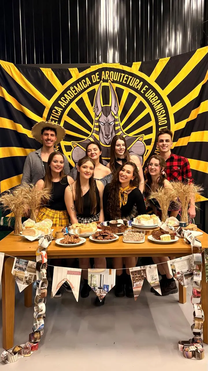 Integrantes da atlética em festa junina diante da bandeira da atlética