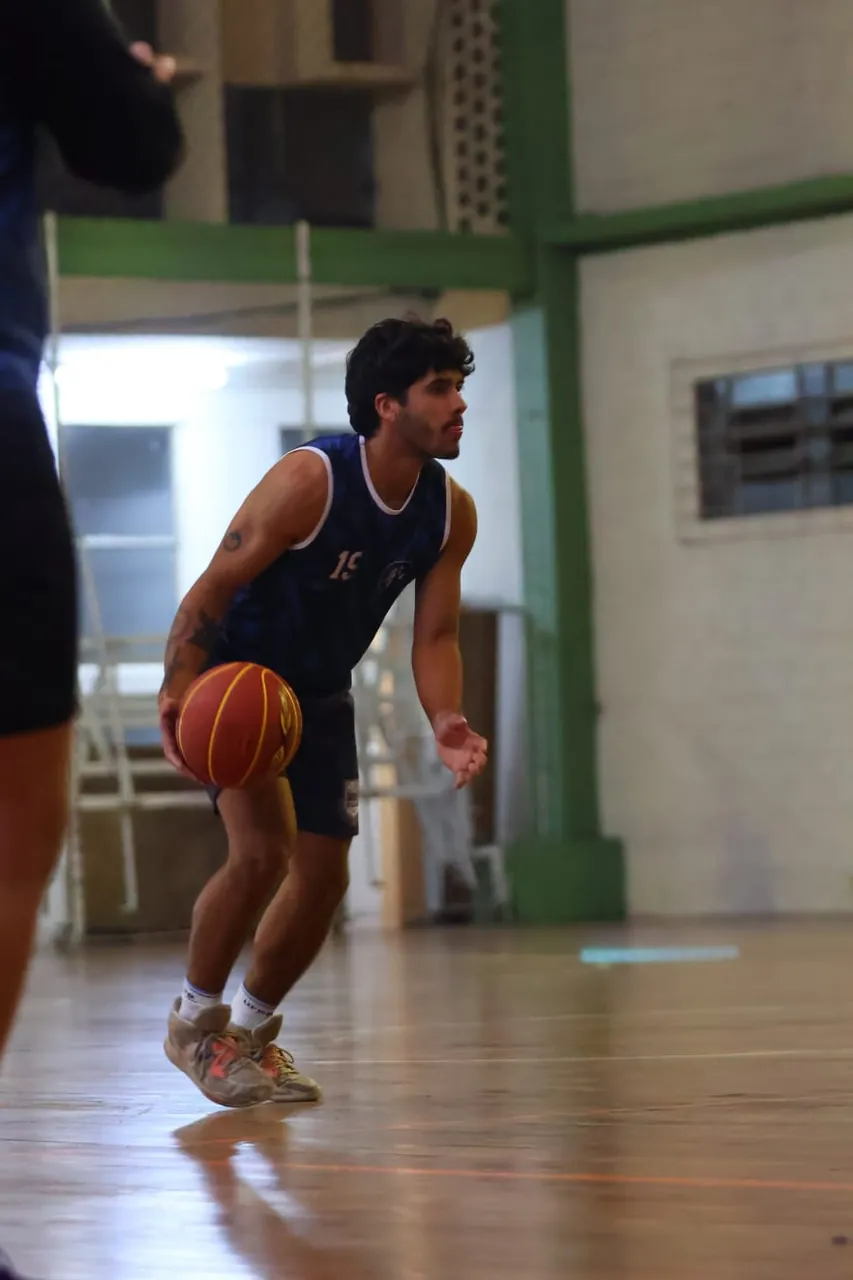 Jogador de basquete da atlética conduzindo a bola na quadra