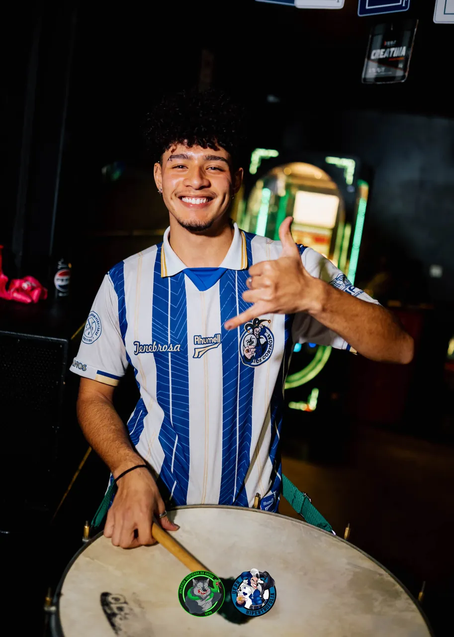 Ritmista da bateria da atlética sorrindo enquanto toca surdo