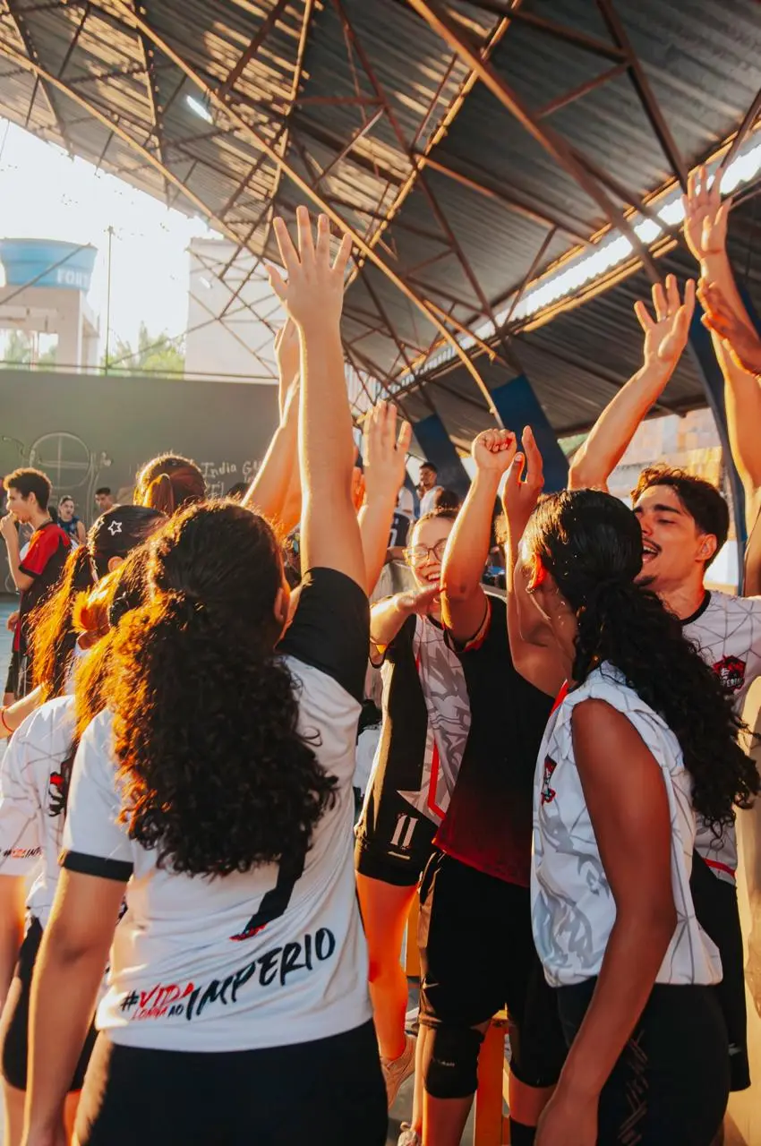 Galera da atlética comemorando de braços erguidos após o jogo