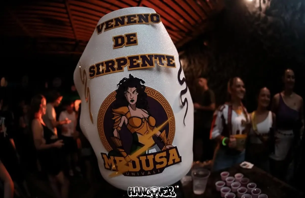 Copo personalizado da atlética erguido no meio da festa