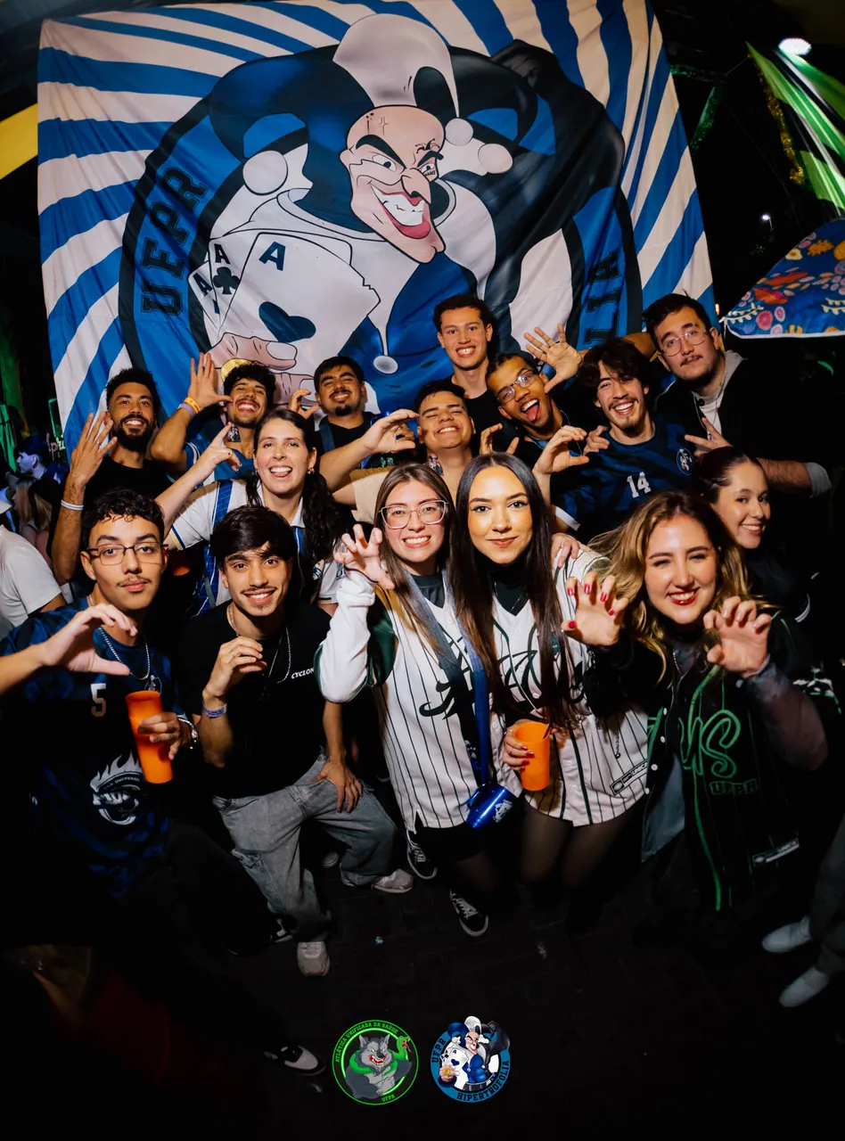 Integrantes da atlética reunidos diante do painel com o mascote